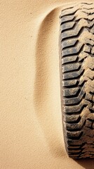 Unique tire tracks create abstract patterns in golden sand on a tranquil beach, revealing nature's...