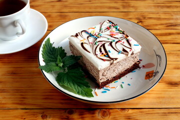 A piece of cake lies on a plate on a wooden table.