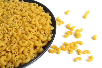  There is a black plate with dry pasta on a white background.