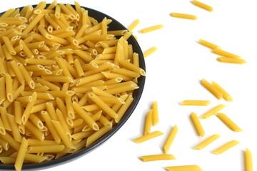 There is a black plate with dry pasta on a white background.	