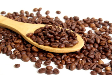 On a white background lies a wooden spoon with coffee beans.	