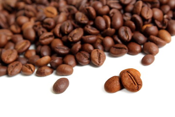 Scattered coffee beans lie on a white background.	