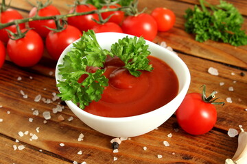 There is a bowl of tomato sauce on the wooden table.	