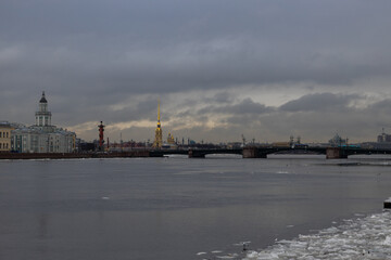 A serene winter morning unfolds over the Neva River in Saint Petersburg, showcasing iconic architecture against a backdrop of dramatic clouds.