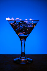 Burning alcoholic drink with ice cubes, on a blue gradient background, vertical frame. Burning...