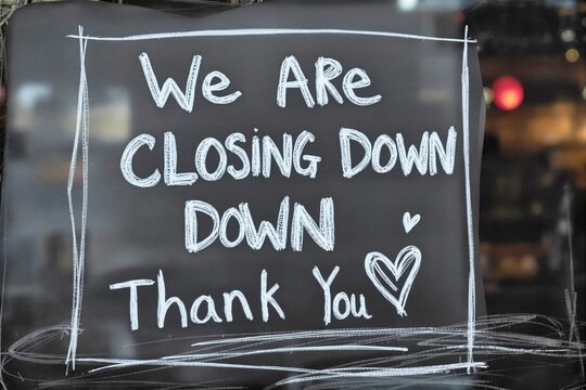 Chalkboard sign announcing the closing of a business with a thank you message written in white letters.