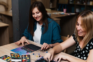 Fototapeta premium Two women engaged in creative art activity in a cozy studio space