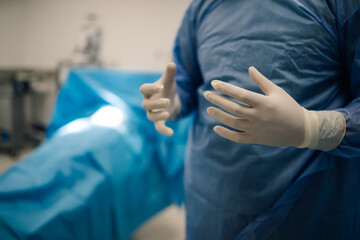 Surgeon preparing for surgery with gloved hands in operating room.