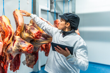 Woman using digital tablet working in a meat processing factory