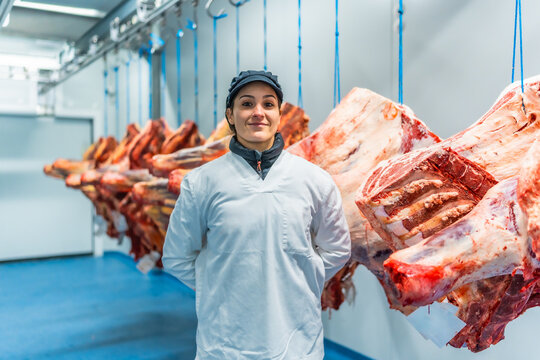 Proud and happy woman butcher in a meat processing factory