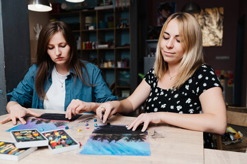 Fototapeta premium Two women creating pastel artwork together in a cozy studio setting