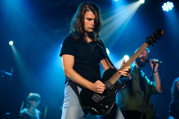 Obraz premium Guitarist performing live on stage with band in blue light