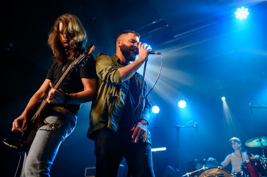 Rock band performing live on stage with energetic singer and guitarist