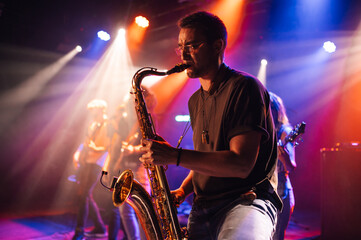 Saxophonist performing live on stage with bandmates in background
