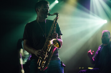 Saxophonist performing live music on stage with band