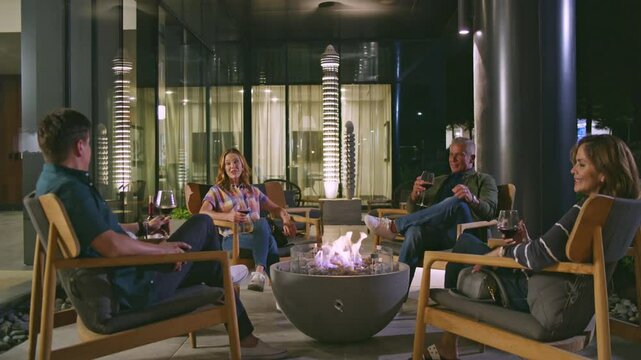 A group of friends drink wine around a firepit in an artist modern setting