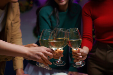 Friends celebrating christmas holidays are making a toast with glasses of white wine