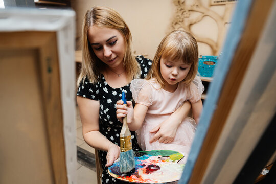 A mother and daughter painting together in a cozy home environment