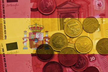 colourful national flag of spain on a euro money banknotes and coins background. finance concept.