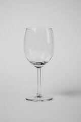 A wine glass is sitting on a white background. The glass is clear and has a stem. Concept of elegance and sophistication, as wine glasses are often associated with fine dining and special occasions