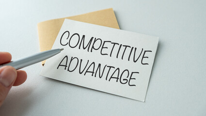 Closeup on businessman holding a card with text COMPETITIVE ADVANTAGE, business concept image with soft focus background