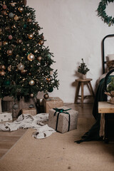 Obraz premium Cozy bedroom decorated for Christmas. Double bed with pillows and blankets against of large green Christmas tree with garlands and toys in a spacious bedroom with white walls