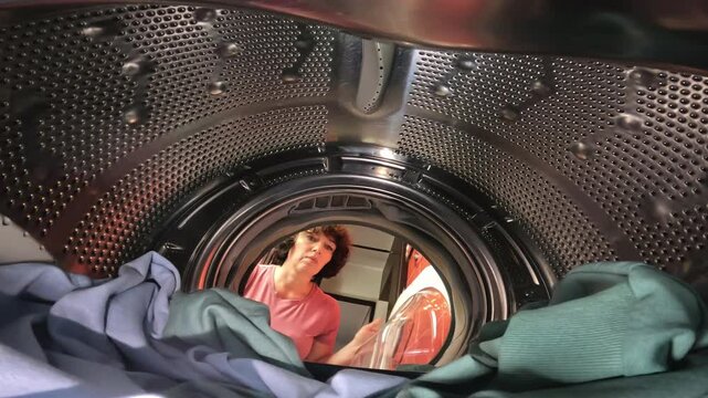 washing machine drum showing woman finding and holding smartphone among laundry. Concept of lost items and household mishaps. washing machine smartphone among laundry washing machine smartphone