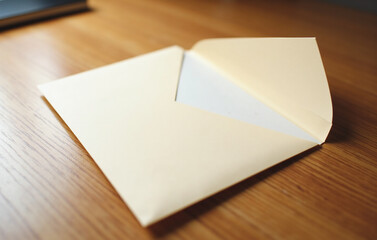 A blank, cream colored envelope lies diagonally on a polished wooden desk