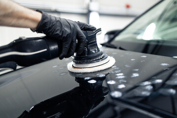 Car detailing and polishing process. Hands of professional car service worker polishing black...