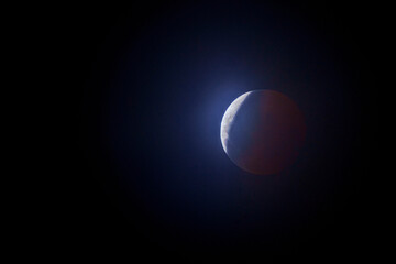 Isolated Full Moon Lunar Eclipse Moon Earth's Shadow Creating Red Cast on The Dark Side And a Glowing Blue Light on the White Surface Ashen Light on a dark background Sky