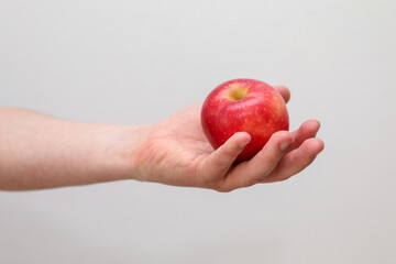 A Caucasian man holds a red apple in a hand - white background