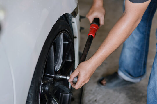 professional mechanic is carefully tightening a car wheel nut.