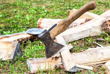 Axe for chopping firewood and chopped firewood lying on the grass