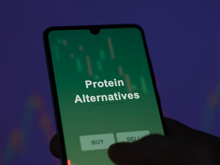 An investor analyzing the protein alternatives etf fund on a screen. A phone shows the prices of Protein Alternatives