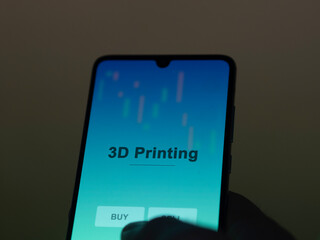 An investor analyzing the 3d printing etf fund on a screen. A phone shows the prices of 3D Printing