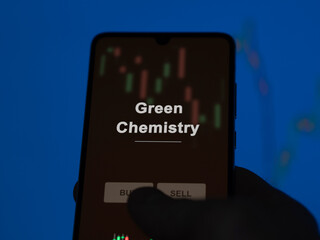An investor analyzing the green chemistry etf fund on a screen. A phone shows the prices of Green Chemistry