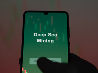 An investor analyzing the deep sea mining etf fund on a screen. A phone shows the prices of Deep Sea Mining