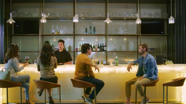 Wide shot of a modern bar with young stylish people drinking
