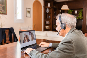 Elderly man video conferencing with family on laptop at home