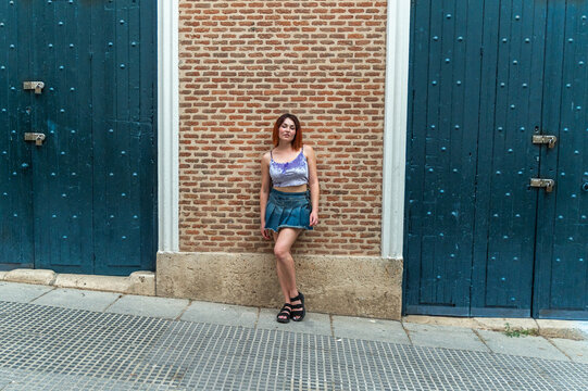 Young woman in relaxed pose by old blue doors