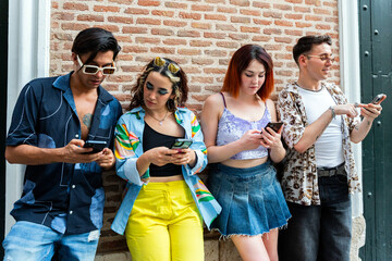Young adults using smartphones against a brick wall backdrop
