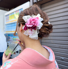 Young woman in traditional Japanese dress walking in a city street, rear view. Japan.