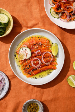 Fresh salmon carpaccio with lime and seed garnish on plate
