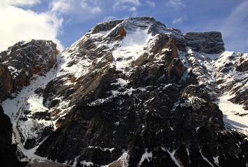 View of the snow-capped mountain peaks against a blue sky with clouds in the Dolomite Alps at Lake Braies in northern Italy