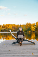 woman working remotely in a beautiful autumn park, sitting on a bench with a laptop. The serene outdoor environment is perfect for remote work or study, surrounded by fall foliage.