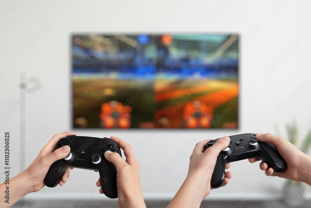 Aufkleber Two players holding gamepads in front of a TV playing a split-screen action game, showcasing interactive multiplayer gaming and dynamic entertainment