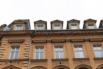 A large multistory building featuring numerous windows, complemented by a white sky present in the...