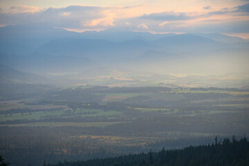 Fototapeta premium Misty mountain valley with layers of hills during sunset.