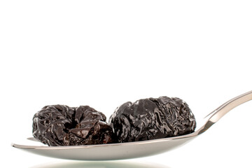 Sweet prunes with a metal spoon, macro, isolated on a white background.