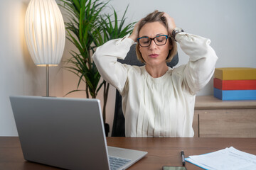Stressed business woman working from home on laptop looking worried, tired and overwhelmed. 